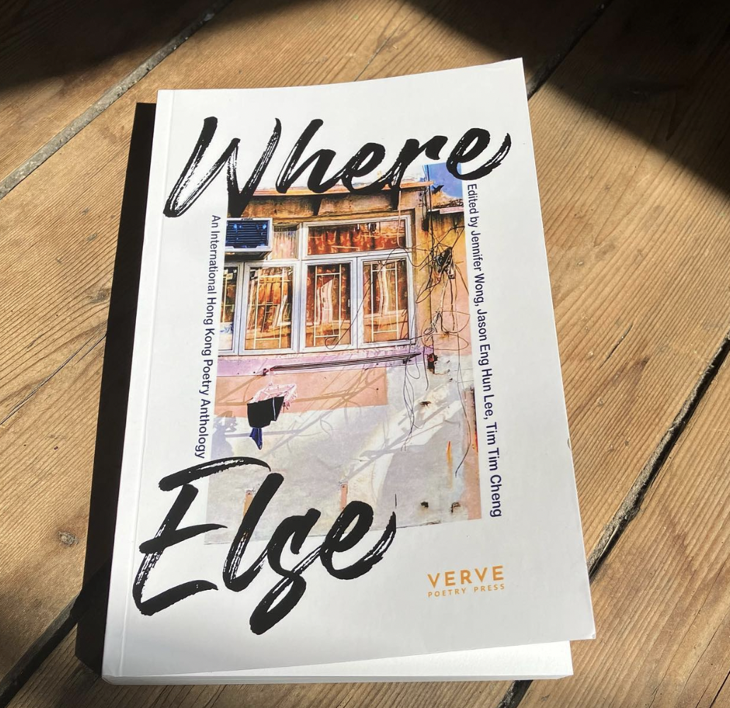 A close-up of the cover of the poetry anthology 'Where Else: An International Hong Kong Poetry Anthology', featuring the title in bold and artistic font, and highlighting the names of the editors: Jennifer Wong, Jason Eng Hun Lee, and Tim Tim Cheng. The book is placed on a wooden surface with natural lighting.